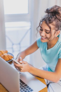 Güzel genç kadın evde mutfak dizüstü bilgisayar ve Mobil Internet bağlantısı çalışır.