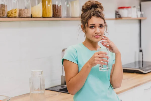 Feliz hermosa joven bebiendo agua. Sonriente modelo femenino caucásico sosteniendo vidrio transparente en su mano . — Foto de Stock