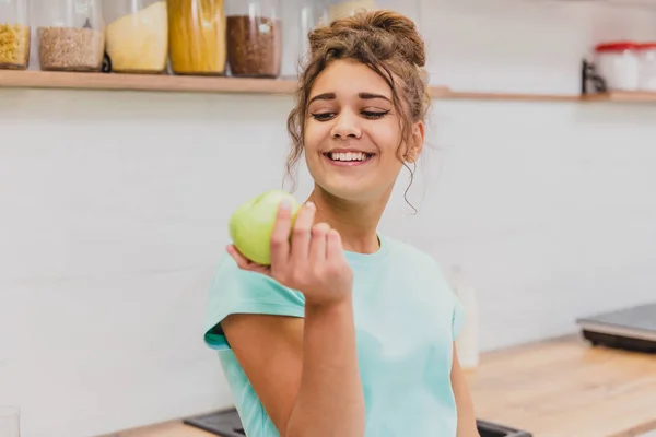 Счастливая молодая женщина ест яблоко на кухне. Диета. Концепция диеты. Здоровое питание . — стоковое фото