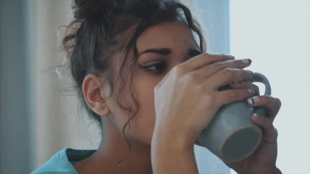 Hermosa, hermosa, joven mujer sosteniendo un vaso de agua dulce y sonriendo mientras está de pie en la cocina por la mañana — Vídeo de stock