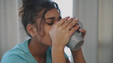 Taze su tutarak ve sabah mutfakta dururken gülümseyen güzel, güzel, genç kadını