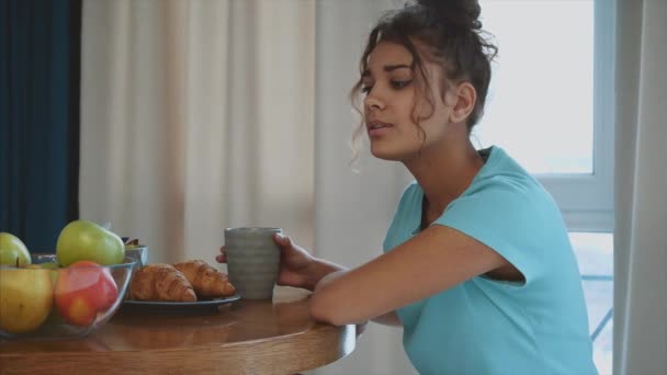Nádherná, krásná, mladá žena drží sklenici čerstvé vody a usmívá se přitom stát v kuchyni ráno — Stock video