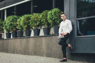 Yakışıklı başarılı iş adamı açık havada stand ofis binası ile kahve yakınındaki