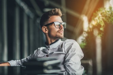 yakışıklı işadamı kafede masada oturan ve uzağa bakarak beyaz gömlekli. Güneş ışığı arka plan