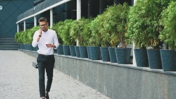 Un joven hombre de negocios con ropa de negocios y gafas va a trabajar . — Vídeos de Stock