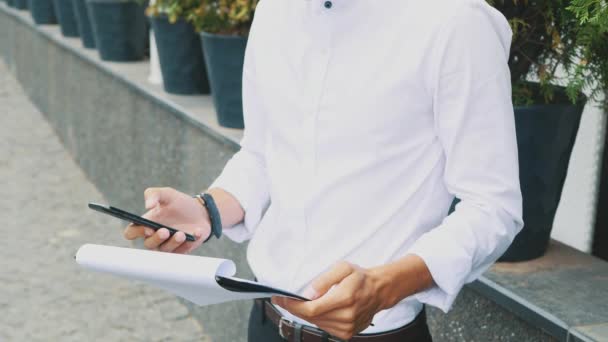 A young businessman dressed in business clothes and glasses stands at the office. — Stock Video