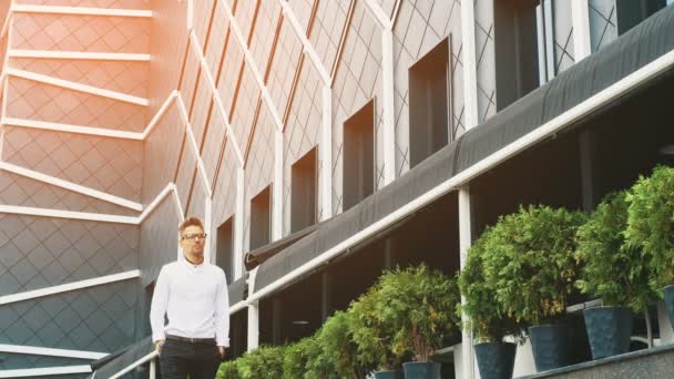 Un joven hombre de negocios vestido con ropa de negocios está en la oficina . — Vídeos de Stock