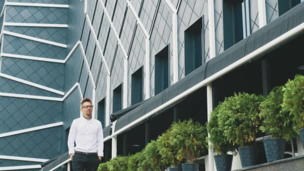 Un joven hombre de negocios vestido con ropa de negocios está en la oficina . — Vídeos de Stock