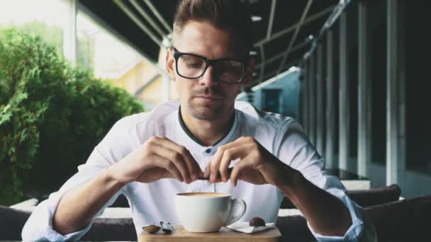 Молодой бизнесмен в деловой одежде и очках сидит в кафе . — стоковое видео