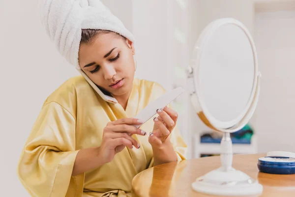 Mladá žena se usměje. Probuzení v ranní šťastná dívka v ručníku na její hlavu v ložnici. Dobrý tón pleti. Přijde pilník. — Stock fotografie