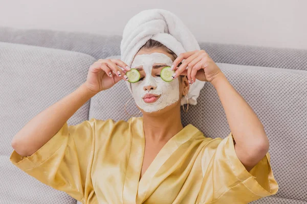 Güzel bir genç kadın bir yüz maskesi ile salatalık gözlerinde yalan spa Center'da alır. Mutlu ve eğlenceli bir sürü alır.