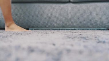 Kadın ayakları yerde bir gri halı üzerinde yürüyor. Tüylü halı yukarıdan. Modern tarz.