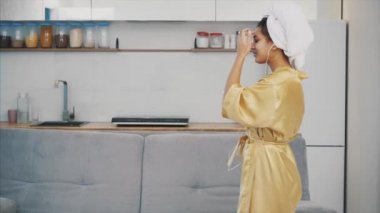 Evde akıllı bir telefonla dans eden kulaklıklı kaygısız bir kadın. Genç kız cep telefonunda yeni şarkılar dinliyor..