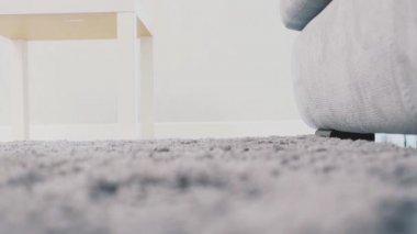 Kadın ayakları yerde bir gri halı üzerinde yürüyor. Tüylü halı yukarıdan. Modern tarz. Yavaş çekim