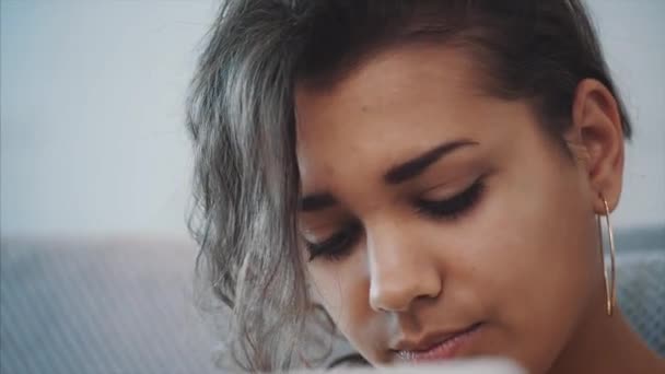 Bruneta, relaxační s její laptop ležet na gauči v jejím bytě. Šťastná mladá žena uvolňující na pohodlné pohovce a pomocí přenosného počítače doma. — Stock video