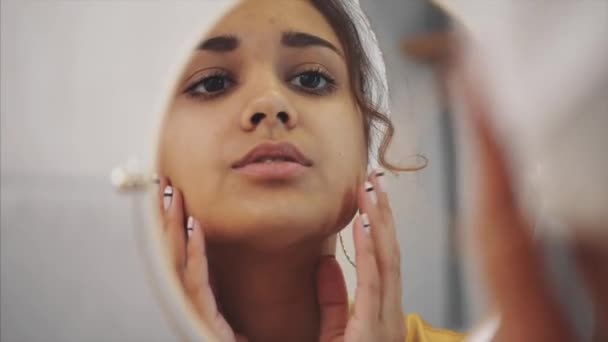Tysta skönhet. Porträtt av en lugn ung dam står framför spegeln och gör henne kinder massage. Hon är charmig och fokuserad. — Stockvideo