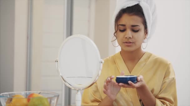 Skönhet, hud vård och folk koncept - leende ung kvinna. Gäller ett ansikte grädde och titta på spegeln hemma. — Stockvideo