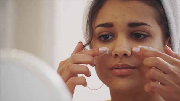 Jonge vrouw glimlacht. Geniet van uw spa wakker in de ochtend. Gelukkig meisje in een handdoek op haar hoofd met een masker op haar gezicht in de slaapkamer — Stockvideo