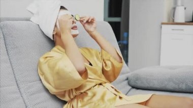 Güzel bir genç kadın bir yüz maskesi ile salatalık gözlerinde yalan spa Center'da alır. Mutlu ve eğlenceli bir sürü alır. Gülümseme