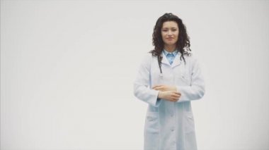 Beyaz bir kadın sana bakmak ve phonendoscope elini tutan bir laboratuvar elbise içinde ciddi bir genç kadında. Bir çok siyah saçlı kadın - beyaz üniforma giyen bir doktor portresi. ,