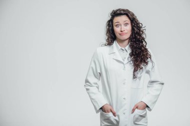 Yatay bir genç güzel doktor kız portresi. Gülümseyen, doğruca kameraya bakıyor. Cebinde elele ve alan bir kopyaya işaret gri bir arka plan üzerinde