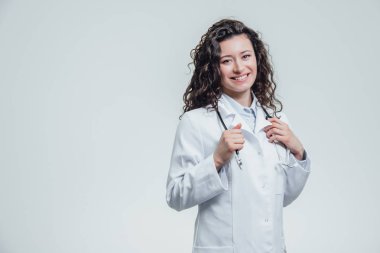 Sana bakmak ve phonendoscope elini tutan bir ciddi genç kadın beyaz bir kadın bir laboratuvar elbise içinde. Bir çok siyah saçlı kadın - beyaz üniforma giyen bir doktor portresi. ,