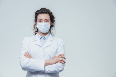 Güzel ve genç bir kadın doktor portresi. Beyaz bir elbise gri bir arka plan var.