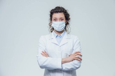 Güzel ve genç bir kadın doktor portresi. Beyaz bir elbise gri bir arka plan var.