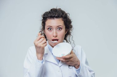 Gri bir arka plan üzerinde beyaz bir soyunma elbise kız doktordur. Uyuşturucu Bağımlılığını kızlar. Hekimlikten bir tabak yemek istiyor.