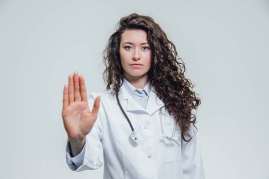 Güzel genç bir kadın doktor el durur. Muhtemelen kadın doktor bir jest son gri bir arka plan üzerinde gösterir.