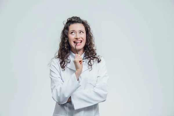 Belle femme souriante - le médecin qui regarde la caméra la moitié du tour. Femme heureuse et drôle portant un portrait médical avant sur un fond gris. Concepts médicaux . — Photo