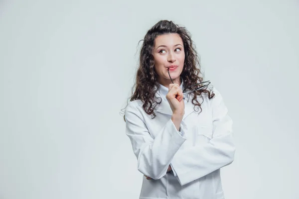 Gülümseyen güzel kadın - yarım dönüş kameraya bakarak doktor. Mutlu ve komik bir tıbbi açık dikey gri bir arka plan üzerinde giyen kadın. Tıbbi kavramları.
