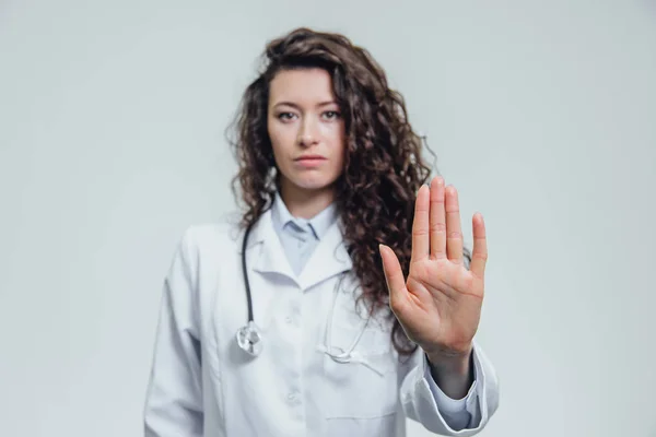 Mladá krásná žena doktor směřují zastaví. Ženský lékař zřejmě ukazuje zarážku gesto šedé pozadí. — Stock fotografie