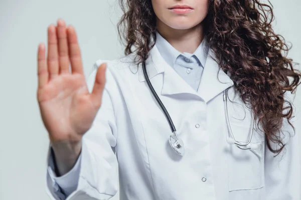 Młoda piękna kobieta lekarz skrzyżowane przystanków. Prawdopodobnie kobieta lekarz pokazuje przystanek gest na szarym tle. — Zdjęcie stockowe