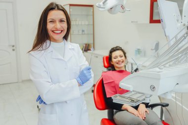 Genç bir kadın ile bir hasta x-ışını diş dişçi ofisinde gösterilen bir dişçi. Konuların tartışılması. Profesyonel bir diş hekimi görüntüsünü kırpılmış.