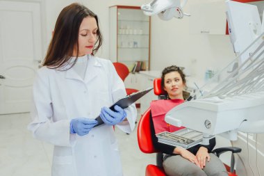 Genç bir kadın ile bir hasta x-ışını diş dişçi ofisinde gösterilen bir dişçi. Konuların tartışılması. Profesyonel bir diş hekimi görüntüsünü kırpılmış.