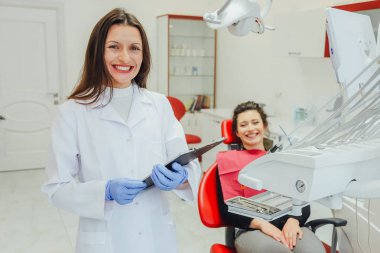 Genç bir kadın ile bir hasta x-ışını diş dişçi ofisinde gösterilen bir dişçi. Konuların tartışılması. Profesyonel bir diş hekimi görüntüsünü kırpılmış.