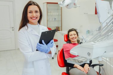 Genç bir kadın ile bir hasta x-ışını diş dişçi ofisinde gösterilen bir dişçi. Konuların tartışılması. Profesyonel bir diş hekimi görüntüsünü kırpılmış.