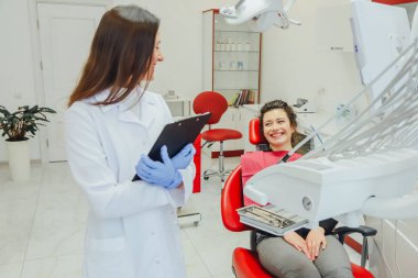 Genç bir kadın ile bir hasta x-ışını diş dişçi ofisinde gösterilen bir dişçi. Konuların tartışılması. Profesyonel bir diş hekimi görüntüsünü kırpılmış.