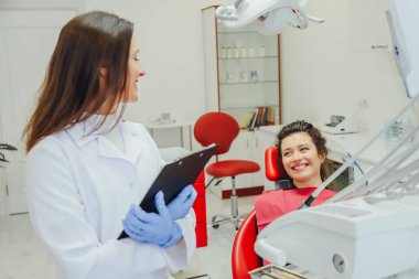 Genç bir kadın ile bir hasta x-ışını diş dişçi ofisinde gösterilen bir dişçi. Konuların tartışılması. Profesyonel bir diş hekimi görüntüsünü kırpılmış.
