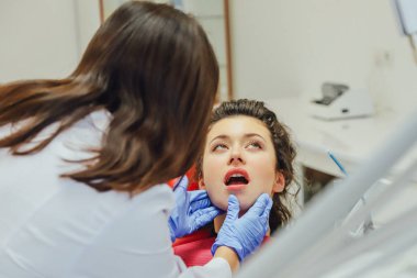 Genç bir kadın ile bir hasta x-ışını diş dişçi ofisinde gösterilen bir dişçi. Konuların tartışılması. Profesyonel bir diş hekimi görüntüsünü kırpılmış.