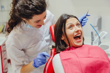 Genç bir kadın ona, bakar diş aletleri korkusu tarafından şok geniş açık gözleri. Bir diş hekimi ve diş tedavisi korkusu kavramı.