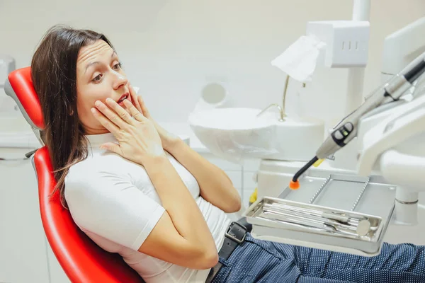 Kobieta w recepcji dentysty w klinice stomatologicznej. Ona siedzi w fotelu na czerwony. Ze strachu pacjenta patrząc w kamerę. — Zdjęcie stockowe