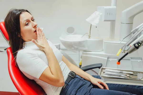 Kobieta w recepcji dentysty w klinice stomatologicznej. Ona siedzi w fotelu na czerwony. Ze strachu pacjenta patrząc w kamerę. — Zdjęcie stockowe