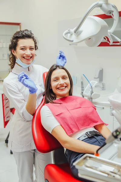 Egy fiatal női orvos öltözve egy maszkot és orvosi kesztyűk. Ennek során a beteg kap egy orvosi tükör és a szonda. Egy fiatal beteg tartják a fogorvos, fogorvosi rendelő. — Stock Fotó