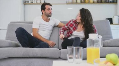 Güzel bir kız ve kanepede oturan ve TV izlerken genç bir adam. İnsanlar kanepede dinlenin. Gözlük ve mavi gömlek genç adam.