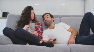 Genç çift kendi dairesinde rahatlatıcı, kanepede yatarken ve film izlerken.