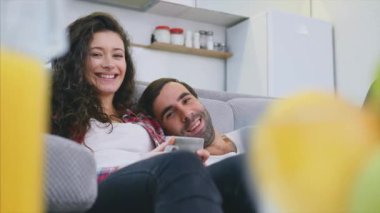 Genç çift kendi dairesinde rahatlatıcı, kanepede yatarken ve film izlerken.