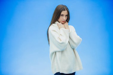 Mutlu bir genç bayan görüntü mavi bir arka plan üzerinde duruyor. Bunlar olurken, onun boynuna ellerini yönde görünüyor.