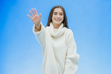 Yalıtılmış bir arka plan üzerinde genç güzel esmer kadın. Parmaklarını yukarıda beş numaralı göstererek. Güvenle ve mutlu bir şekilde gülümseyerek.